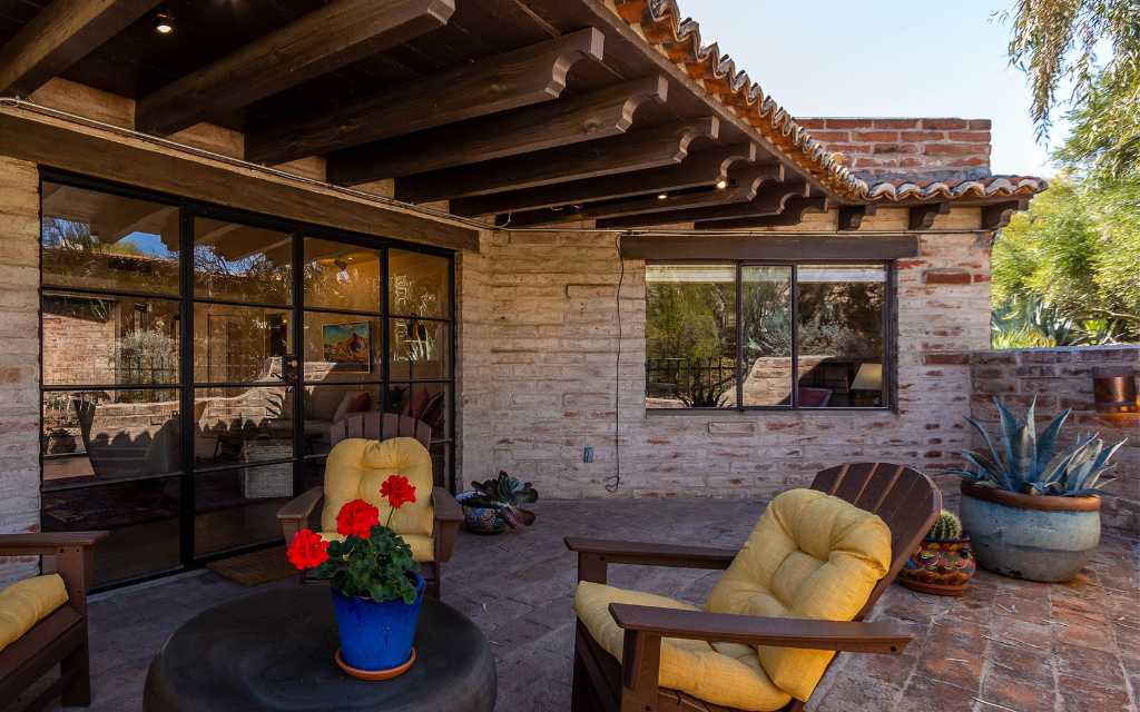 Patio of a townhouse designed by Juan Worner Baz in Tucson. Burnt adobe walls of the home with a tile roof overhang and eaves with carved ends. Located in Catalina Foothills, Tucson, Arizona.