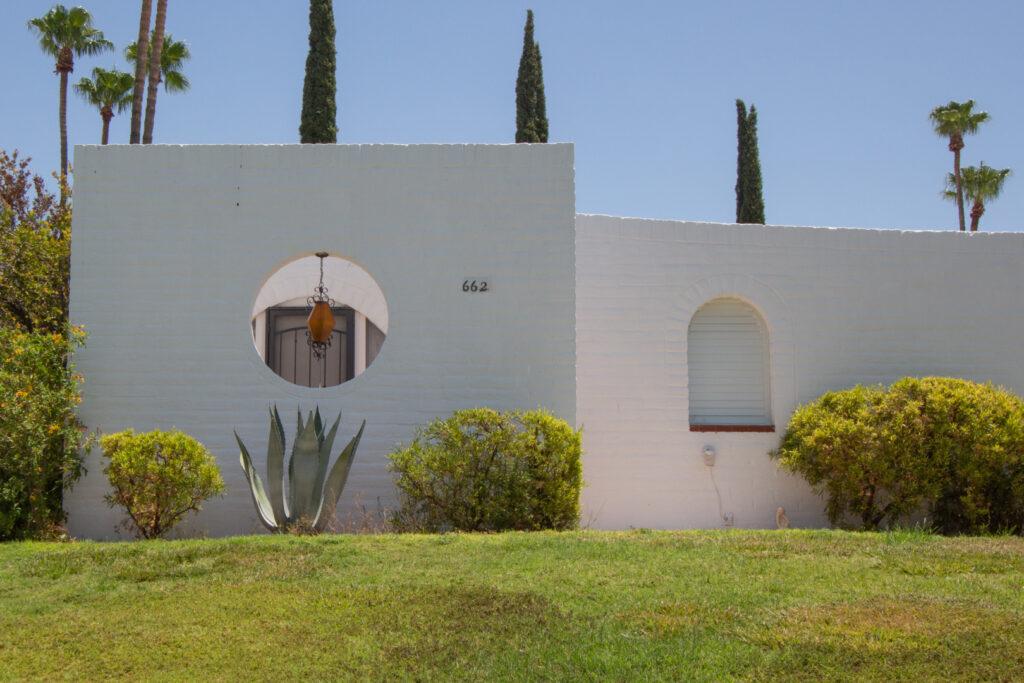 White painted burnt adobe buildings feature arches and round openings to compliment to verdant landscape.