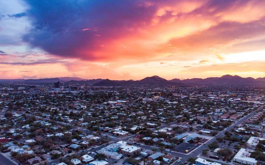 Aerial view of neighborhoods in Tucson situated on a grid with the Tucson Mountains in the background