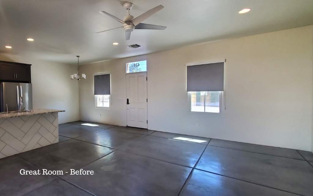 Empty great room with white walls and concrete floors that has not been staged