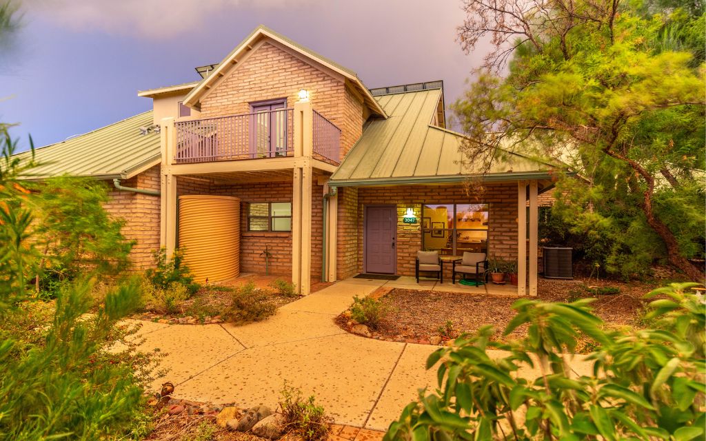 Milagro Cohousing in Tucson featuring 2-story adobe home with a green metal roof and water harvesting cistern